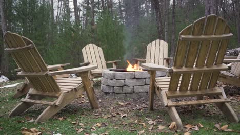 Close-up-of-6-empty-lawn-chairs-around-a-burning-fire-pit