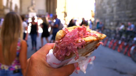 POV-of-a-man-walking-with-a-Italian-salami-sandwich-in-the-street-of-Florence,-Italy