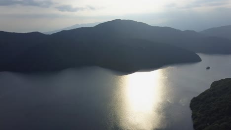 Aerial-view-of-sun-reflections-over-lake-ashi-with-ship-panoroma