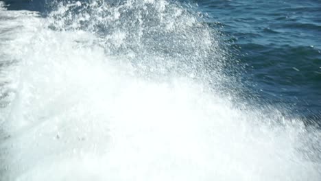 Close-up-of-ocean-sea-white-foamy-waves-behind-boat