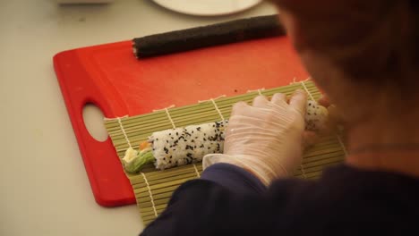 SLOWMO---Japanese-chef-preparing-sushi-rolls-with-salmon,-avocado-and-sesame-seeds