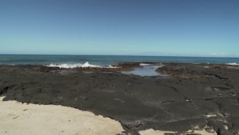 Waves-hitting-black-lava-rock-formations-on-a-Hawaiian-island