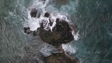 Aerial-cenital-shot-of-waves-crashing-on-rocks-formations-in-Zipolite-beach,-Oaxaca