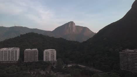 Sunrise-aerial-downward-movement-with-the-Corcovado-mountain-in-Rio-de-Janeiro-behind-a-mountain-range-and-residential-area-and-the-scene-reflecting-in-the-lake-in-the-foreground