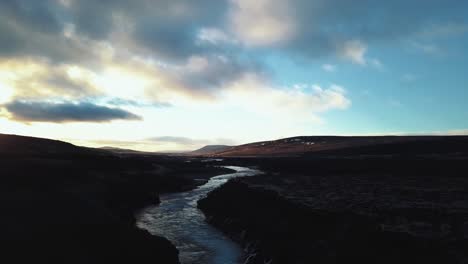 Drohne-Mit-Filmischen-Bewegungen-Zeigt-Den-Wunderschönen-Isländischen-Wasserfall-Hraunfossar-Im-Sonnenuntergangslicht-Aus-Mehreren-Winkeln