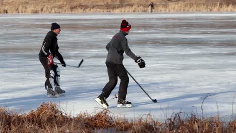 Wide-angle-following-action-shot-of-friends-playing-pond-hockey