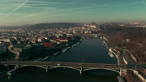 Vuelo-De-Drones-Sobre-El-Río-Vlatava-De-Praga-Que-Muestra-Puentes-Parque-Del-Castillo-Y-Edificios-Sol-De-Invierno