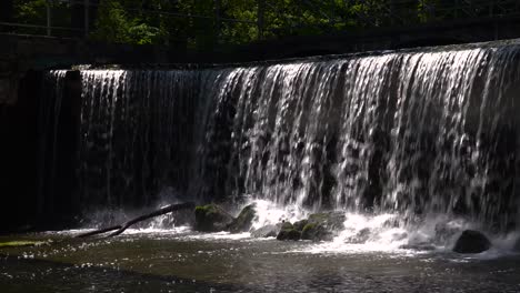 Static-view-of-man-made-waterfall-gently-falling-on-rocks-and-trees-in-park-setting