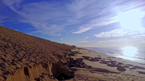 Aerial-shot-dolly-in-low-level-and-and-pedestal-up,-Pyla-dune-on-left-and-sea-on-right,-blue-sky-above,-France