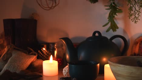 Relaxing-background-detail-shot-of-an-herbal-tea-shop,-with-candles-with-flickering-flames,-a-tea-pot,-a-cup-with-steam-coming-out,-herbs-hanging-and-books
