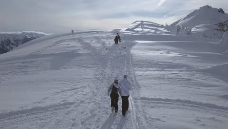 Luftaufnahme-Eines-Paares,-Das-Einen-Schneebedeckten-Berg-Hinaufsteigt-Und-Der-Mann-Beim-Gehen-Seine-Hand-Auf-Ihre-Schulter-Legt