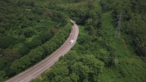 Aerial-view-of-countryside-road-passing-through-the-lush-greenery-and-foliage-tropical-rain-forest-mountain-landscape