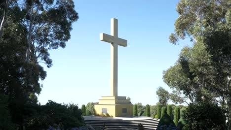 Large-remembrance-cross-in-sunlight-framed-by-tall-trees-either-side