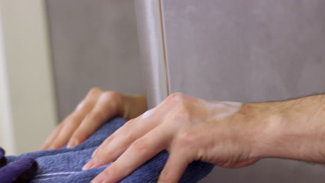 Nahaufnahme-Einer-Kaukasischen-Männlichen-Hand,-Die-Vor-Dem-Badezimmerspiegel-Nach-Einem-Handtuch-Sucht,-Während-Eine-Andere-Hand-Es-Auf-Der-Anderen-Seite-Ergreift
