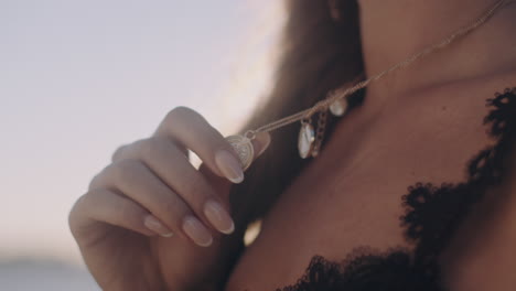 Beautiful-woman-holding-her-pendant-decoration-Sunset-close-up-shot