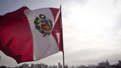 SLOW-MOTION:-Flag-of-Peru-waving-in-wind-over-the-cityscape-of-Lima