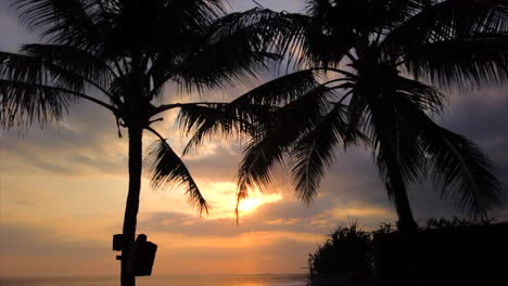 Zeitraffer-Mit-Hyperbewegung,-Sonnenuntergang-Auf-Bali,-Silhouette-Von-Palmen-Und-Menschen,-Die-Den-Sonnenuntergang-Genießen