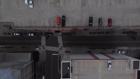 Aerial-footage-over-city-flying-over-town-and-cars-with-people-and-parking-garages