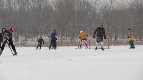 Eine-Zeitlupen-Weitwinkelaufnahme-Einer-Gruppe-Von-Erwachsenen-Und-Kindern,-Die-Teichhockey-Spielen
