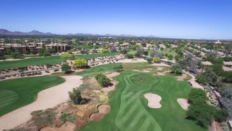 Aerial-hight-angle-pulls-back-from-foursome-on-the-green-to-reveal-the-fairway,-sandtraps-and-rough,-Scottsdale,-Arizona-Concept:-exercise,-tourism,-green