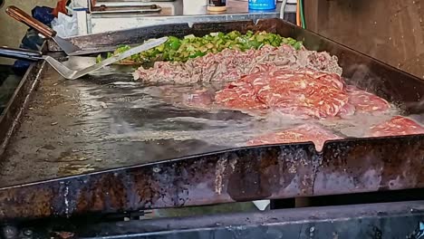 close-up-raw-meat-on-hotplate-griddle-sizzling-with-grease-and-fat-seeping-out-and-smoke-rising