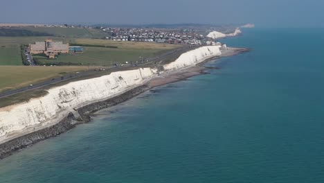 Wide-aerial-view-of-the-A259-coast-road-near-Brighton,-with-the-Blind-Veterans-UK-building-near-Rottingdean,-Chalk-cliffs-and-coastline