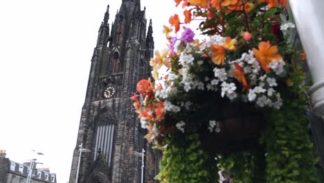 Gothic-cathedral-being-revealed-behind-bouquet-of-flowers-in-Edinburgh,-Scotland-panning-left