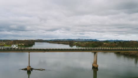 Empty-flatbed-truck-crosses-river-bridge,-Waikato-New-Zealand