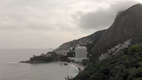 Aerial-view-on-Vidigal-beach-and-the-Two-Brothers-mountain-with-the-shanty-town-community-in-the-background-and-a-luxury-hotel-in-the-foreground-on-a-gray-overcast-day