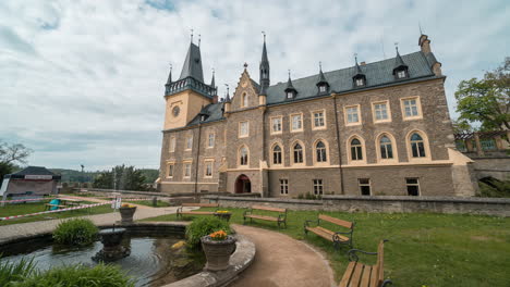 Tschechischer-Renaissancepalast-Mit-Einem-Brunnen-Und-Menschen-Draußen-Mit-Geschwollenen-Wolken,-Die-über-Den-Türkisfarbenen-Himmel-Rauschen,-Zeitraffer