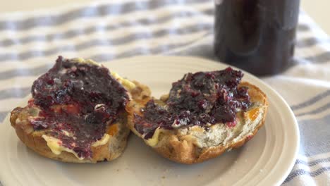 Slow-motion-pan-across-hot-cross-buns-sitting-on-plate-with-thick-butter-and-jam-during-Easter