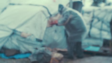 Un-Viejo-Refugiado-Arreglando-Su-Tienda-De-Campaña-En-El-Olivar-De-La-&#39;jungla&#39;-Del-Campamento-De-Refugiados-De-Moria-Durante-Condiciones-Climáticas-Sombrías
