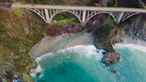 Overhead-aerial-view-of-a-car-driving-over-Bixby-Creek-Bridge-in-Big-Sur-on-State-Route-1-in-California
