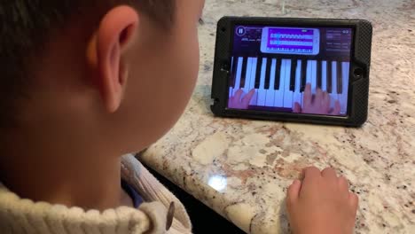 Niño-Aprendiendo-A-Tocar-El-Piano-En-El-Ipad-Usando-Una-Aplicación-De-Itunes-Llamada-&quot;simplemente-Piano&quot;-De-Joy-Tunes
