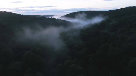 Early-morning-fog-rolls-around-a-forested-valley