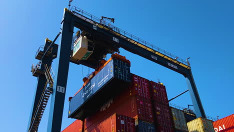 A-container-is-being-lifting-up-with-the-konecrane-over-the-hundreds-of-containers-at-the-port,-low-angle-view