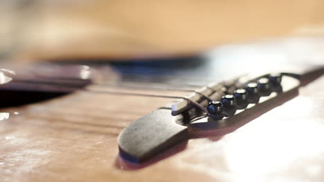 Eine-Große-Nahaufnahme-Von-Saiten-Einer-Bassgitarre-Mit-Ihrer-Basis,-Lichtreflexionen-Und-Fokusverlagerung-Auf-Die-Gitarre