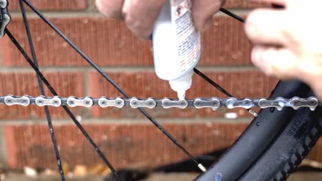Close-up-of-a-mechanic-placing-lubricant-on-a-freshly-cleaned-bicycle-chain-as-a-part-of-routine-maintenance