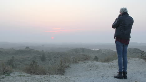 Wide-shot-of-a-landscape-photographer-man-taking-photos-in-nature-at-sunset-or-sunrise
