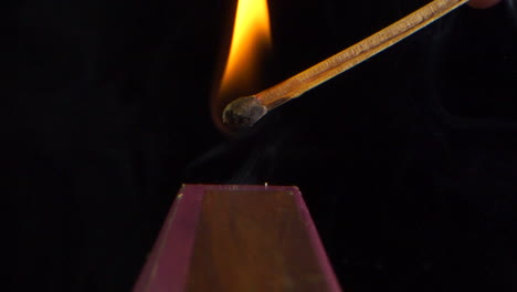 Ignition-and-burning-in-slow-motion-of-a-match-on-the-side-of-the-box,-black-background