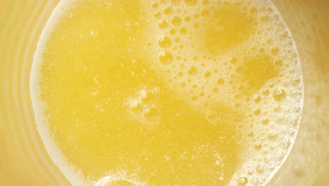 Top-view-of-tablets-dissolving-in-yellow-drink,-water-fizzing-background