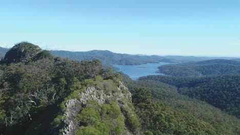 Aerial-view-of-a-pinnacle,-headland-over-a-magnificent-lake-surrounded-by-endless-forest