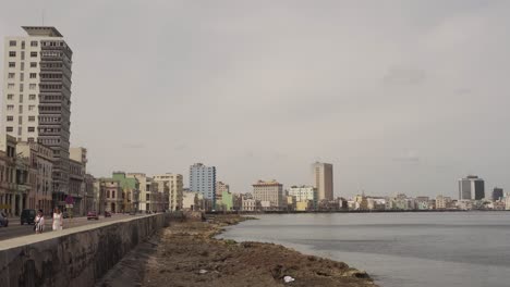 Paseo-Marítimo-Del-Famoso-Malecón-De-La-Habana-Durante-El-Día-Con-Los-Lugareños-En-La-Calle,-Cuba