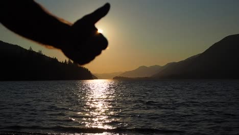 Sunset-on-a-lake-with-mountains-in-the-background-with-a-guy-giving-the-thumbs-up-in-Silhouette