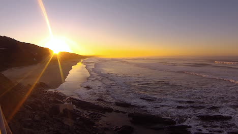 TimeLapse---Stunning-golden-sunrise-over-long-stretch-of-beach,-waves-rolling-in