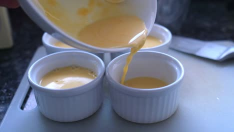 making-french-dessert-cream-brulee,-pouring-the-mixture-into-little-bowl-in-slow-motion