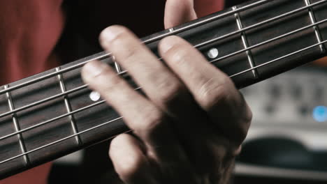 Musician-plays-bass-guitar-in-his-own-studio,-close-up-of-the-hand-on-the-neck