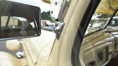 Close-up-detail-of-the-side-view-mirror-on-a-yellow-classic-car