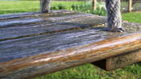 CLOSE-UP-view-of-wooden-swing-seat-gently-swaying-in-the-wind