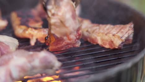 Slow-Motion-of-Tongs-Flipping-Sizzling-Meat-on-Fiery-and-Smokey-BBQ-Grill